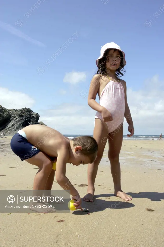 Young girl and boy playing on the beach, Cornwall, England