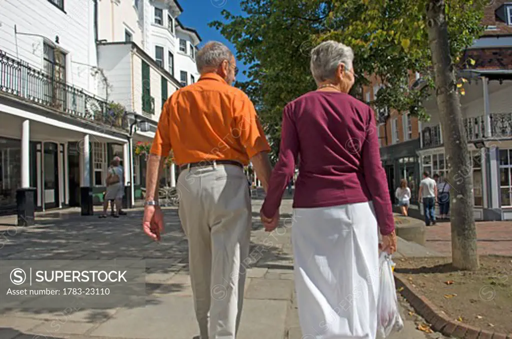 Rear view of elderly couple walking down the Pantiles., Tunbridge Wells, Kent, England, United Kingdom.