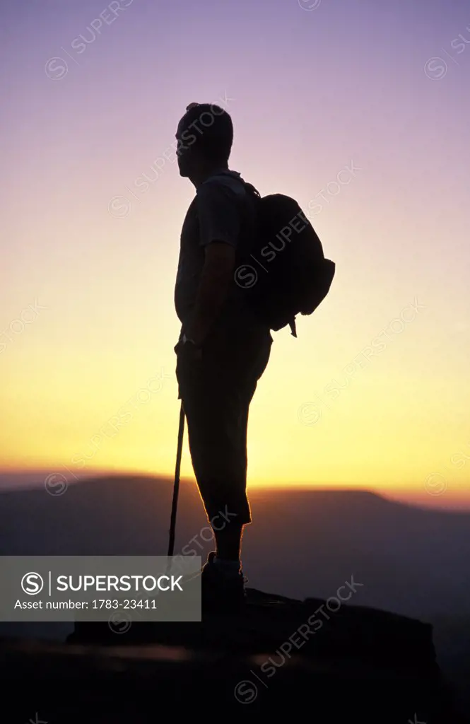 Silhouetted man standing on mountain peak, Brecon Beacons National Park, Black Mountains, Wales