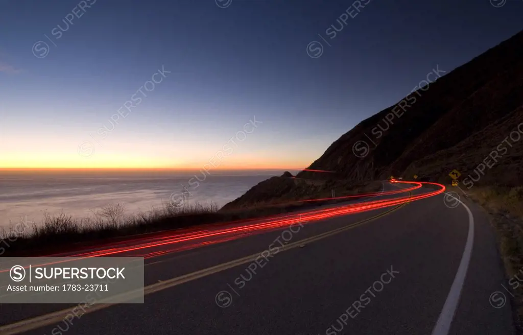 Car going down the Big Sur coastal road at dusk, Highway 1, California