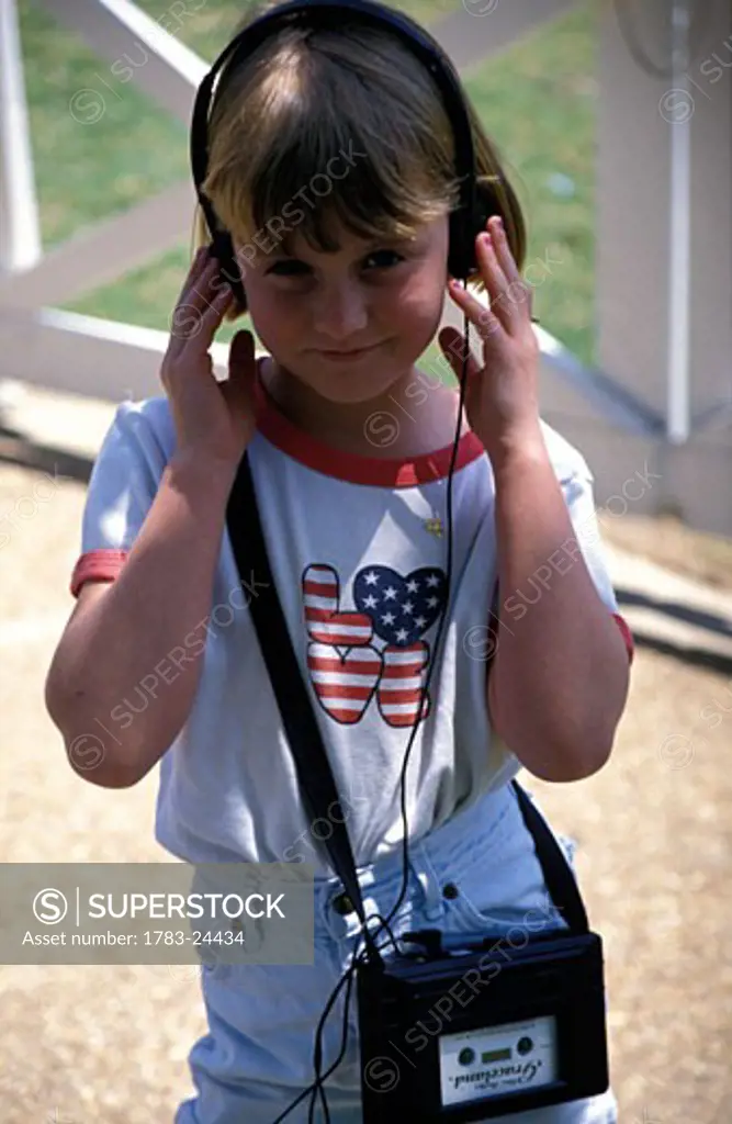 Girl listening to headset with stars and stripes t-shirt, Graceland, Memphis, USA.