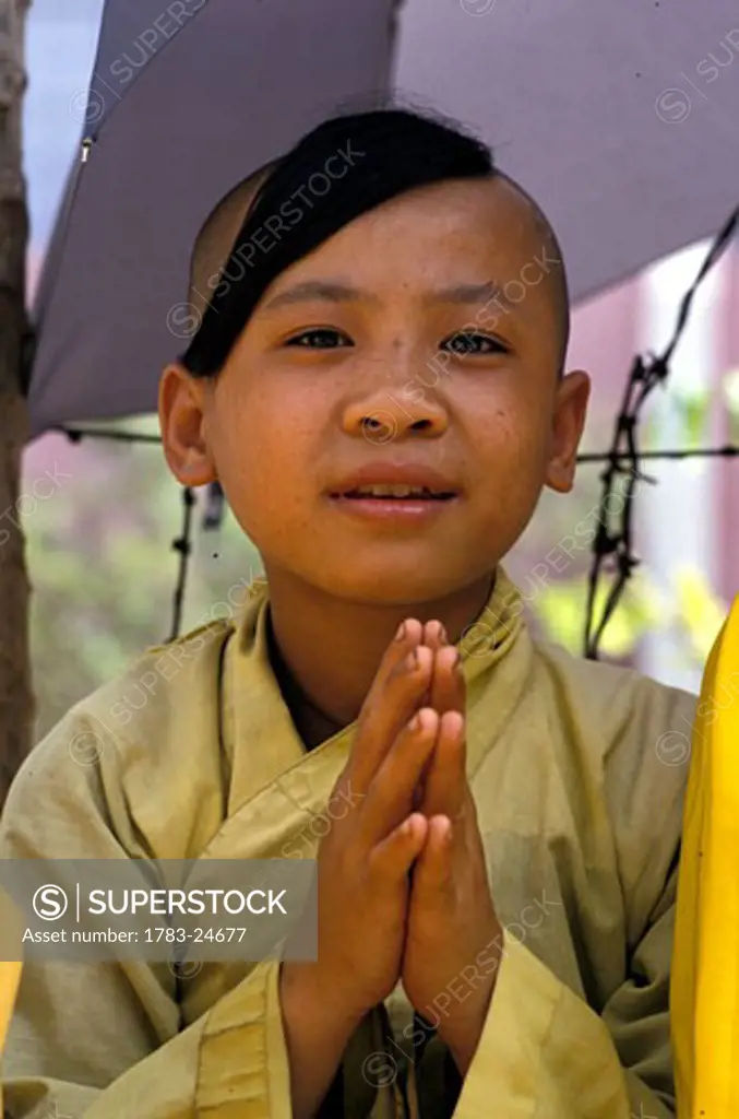 Monk waiting for alms outside a temple during Tot festival, Vietnam.