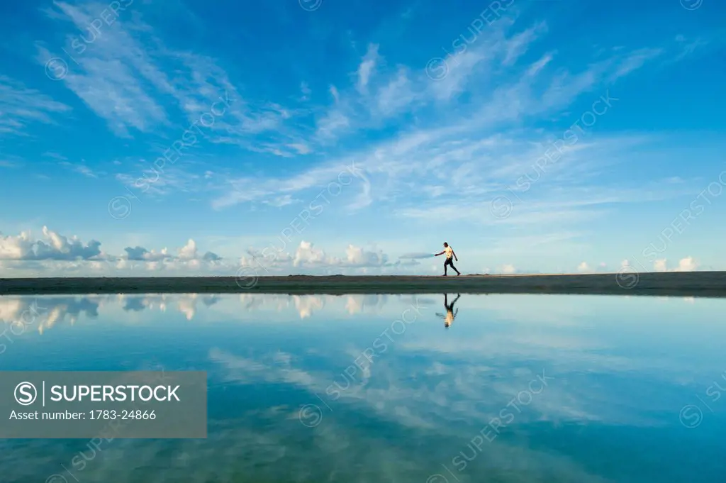 Man walking past shallow pond, Brighton Beach, Barbados.