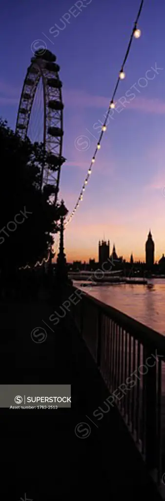 Looking along the Thames Path to the London Eye and The Houses of Parliament at dusk, London, UK.