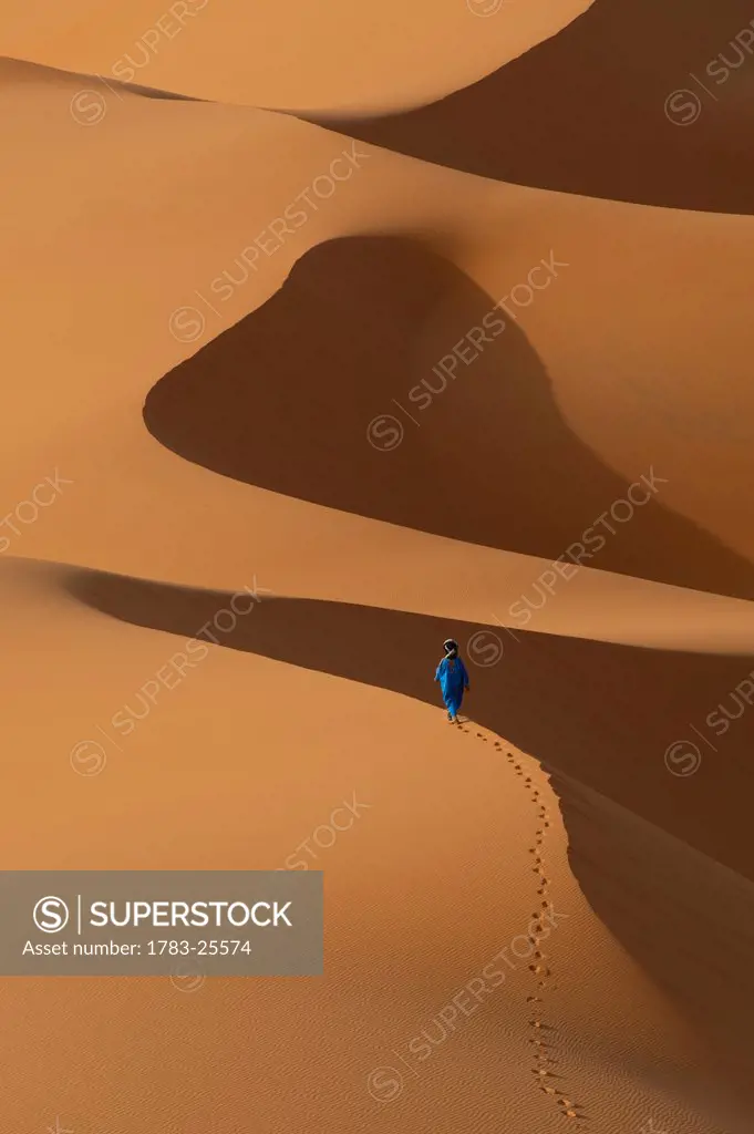 Berber walking across sand dunes in the Erg Chebbi area of the Sahara Desert