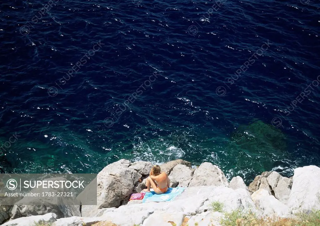 Woman sunbathing on rocks, Hydra, The Argos_Saronics, Greece