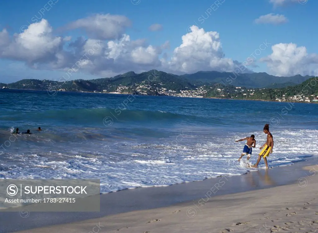 Two boys playing in surf on beach, Grenada