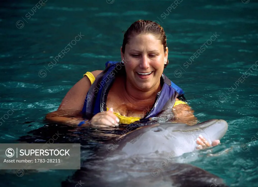 Tourist with dolphin at Dolphin Cove,, Ocho Rios, Jamaica. 