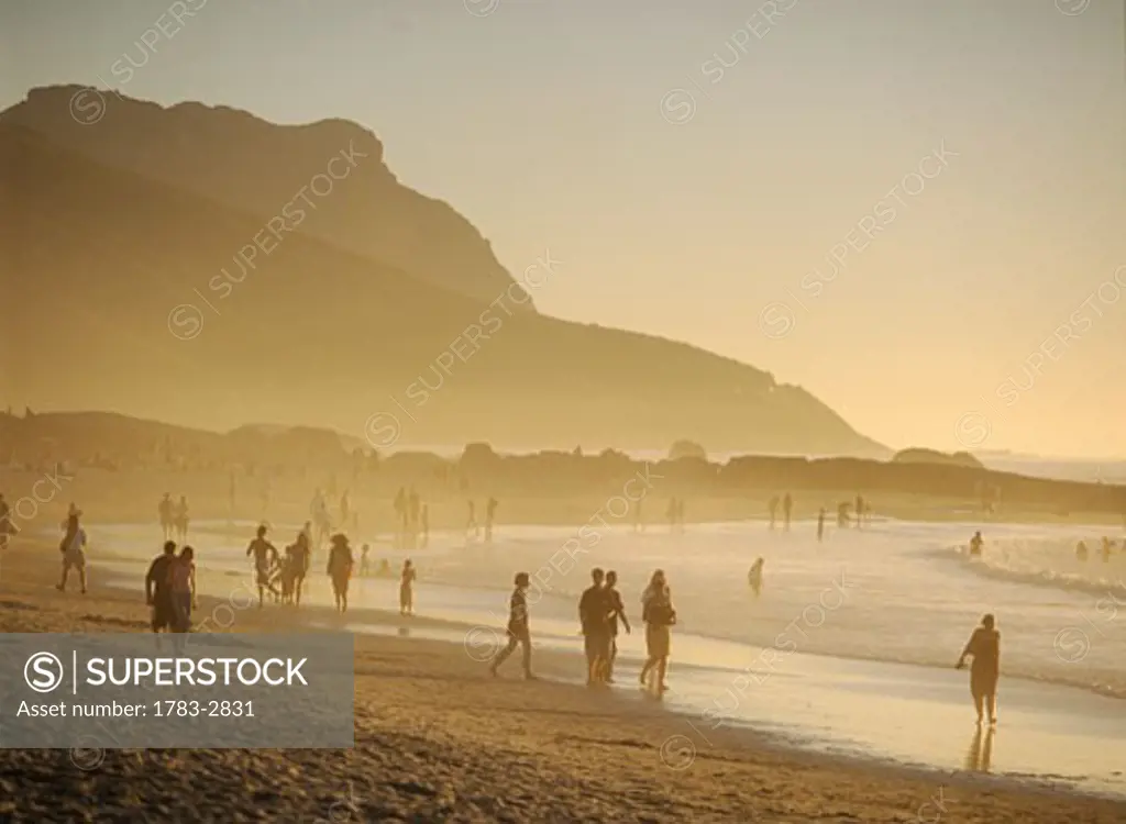 People walking along the beach at dusk, Camps Bay, Cape Town, South Africa.    