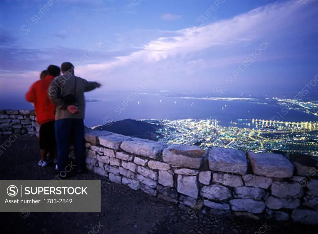 Family admiring the view of Cape Town at dusk as seen from the top of Table Mountain, South Africa. 
