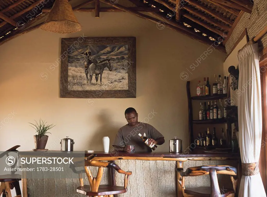 Young man preparing drink in bar, Kenya