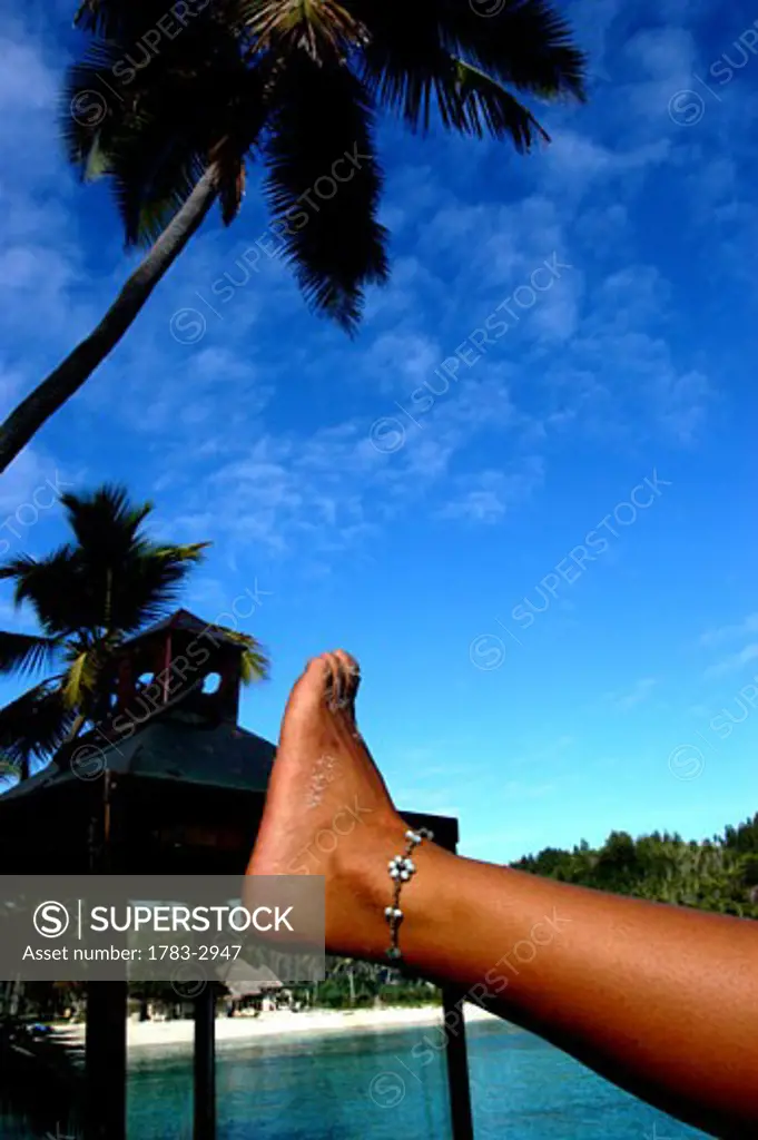 Guest's foot on sundeck lamp. Overlooking beach and villa's North Island Seychelles