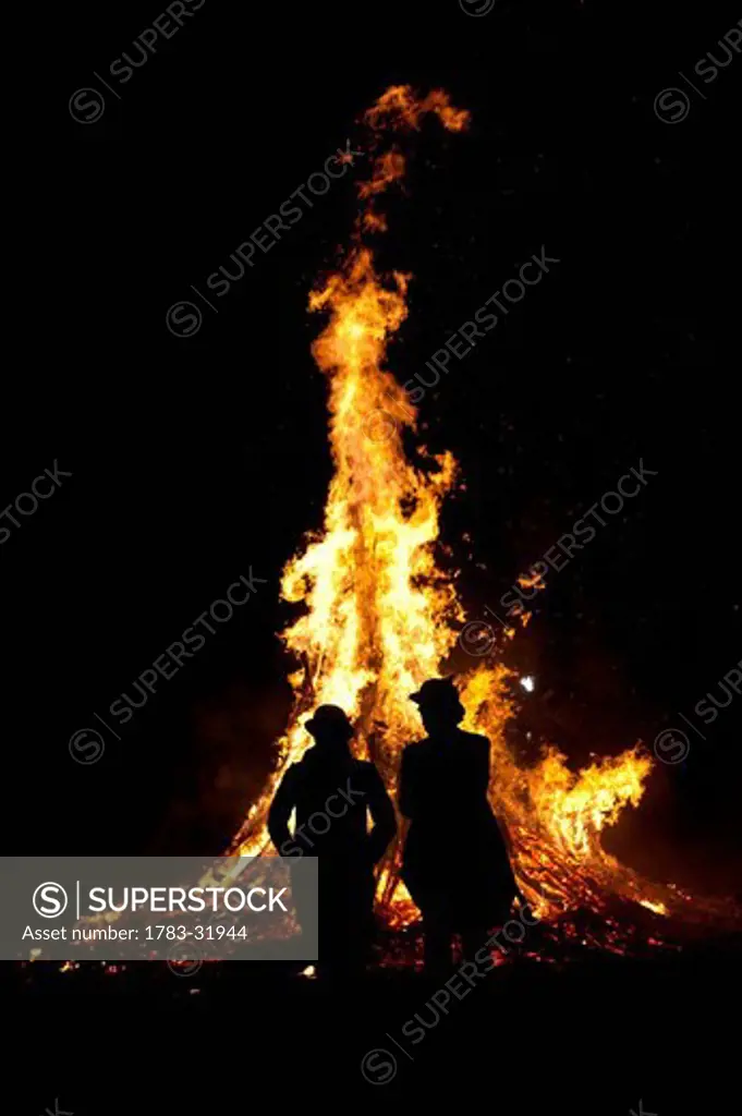 Silhouette of man and woman in front of large bonfire at Battle Bonfire nightEast Sussex, England. Silhouette of man and woman in front of large bonfire at Battle Bonfire night
