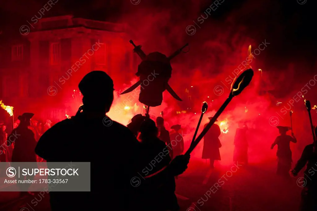 Silhouettes Of Pirates From Bonfire Society Lit By Red Flare Marching Through The Streets Of Seaford, East Sussex, Uk