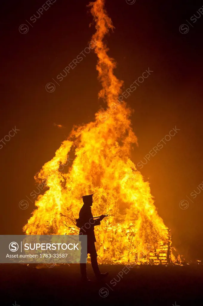 Silhouette Of Man In Military Unifrom In Front Of Large Bonfire At Barcombe Bonfire Night, Barcombe, East Sussex, Uk