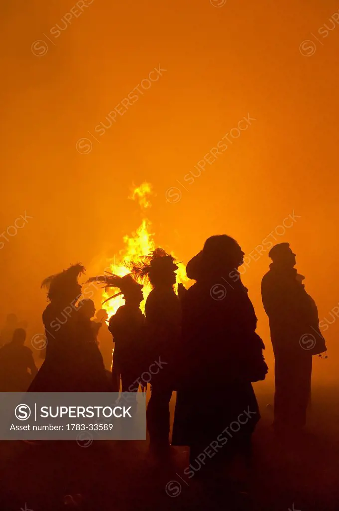 Silhouette Of People In Front Of Large Bonfire Watching Fireworks Display At Barcombe Bonfire Night, Barcombe, East Sussex, Uk