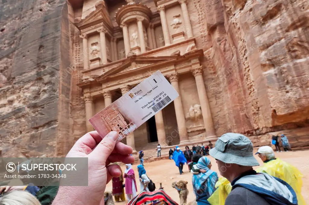Tourist Holds Up His Expensive Entrance Ticket To Petra Outside The Temple Or Treasury In Petra, Jordan, Middle East