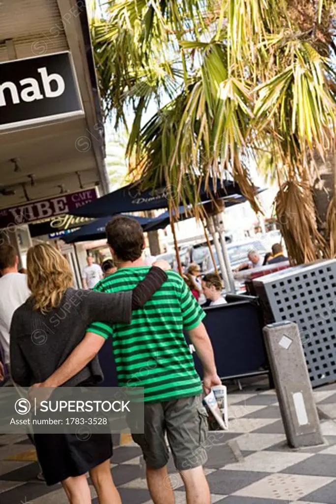Couple walking near sidewalk cafe in St Kilda, Melbourne, Australia
