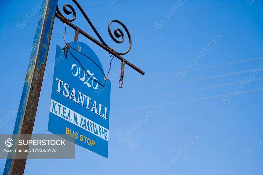 Bus stop sign with ouzo advert on it tsantali brand; ierissos halkidiki greece