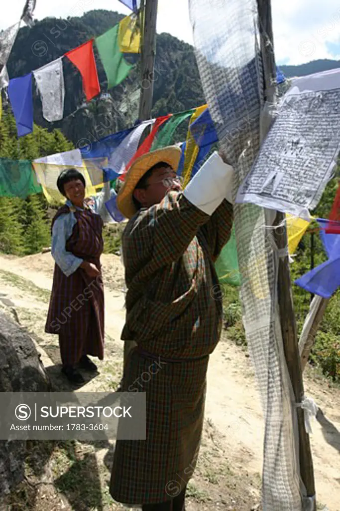 People hanging prayer flags in Bhutan, Taktshang Goemba Tigers Nest Monastery, Bhutan