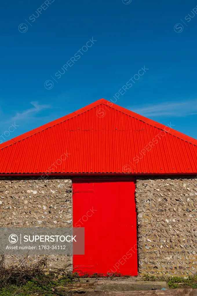 England, East Sussex, Bright red barn door and roof; Seven Sisters National Park
