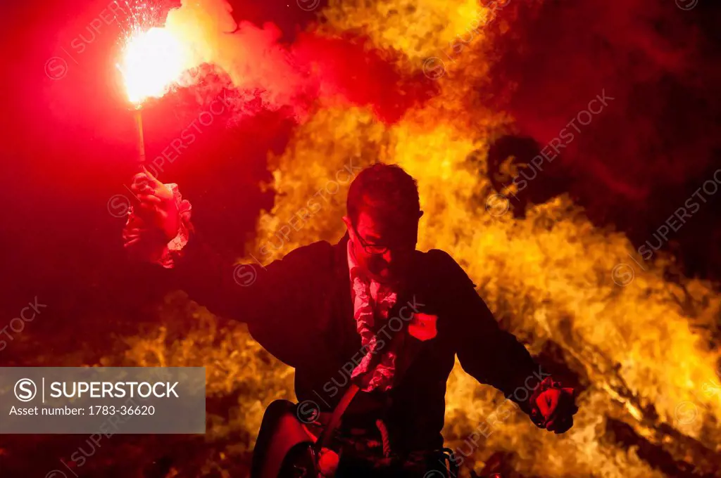 Man Dressed As Pirate From Southover Bonfire Society In Front Of Large Bonfire Holding Red Flare, Bonfire Night, Lewes, East Sussex, Uk