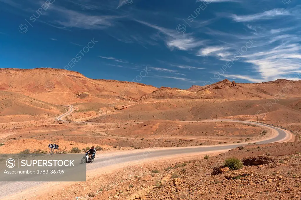 Morocco, Two men motorbike driving through desolate scenery; Valley of Roses