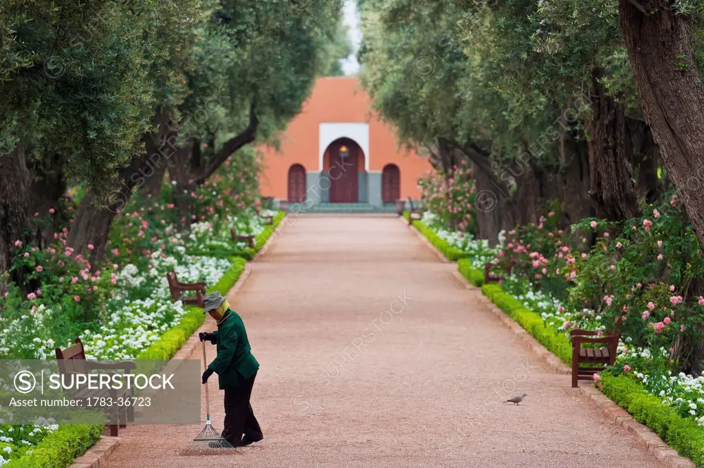Morocco, Man sweeping garden alley; Marrakech