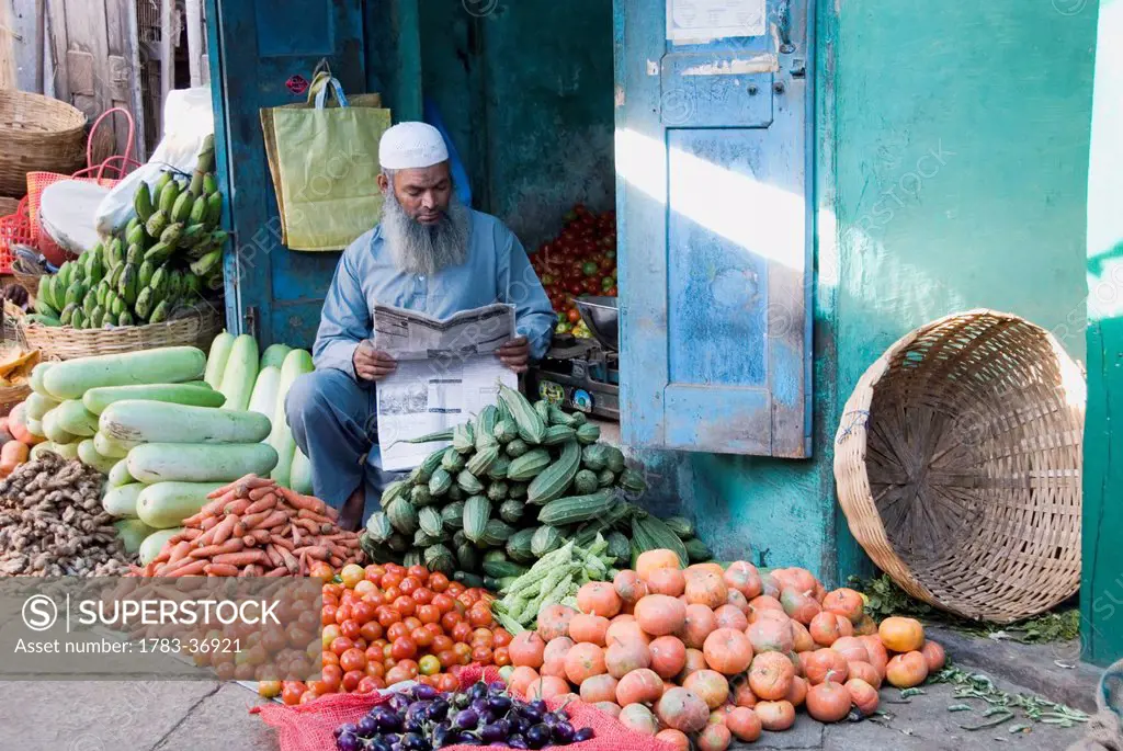 Muslim Vegetable Seller Reading The Newspaper At Devaraja Market In Mysore, Karnataka, India