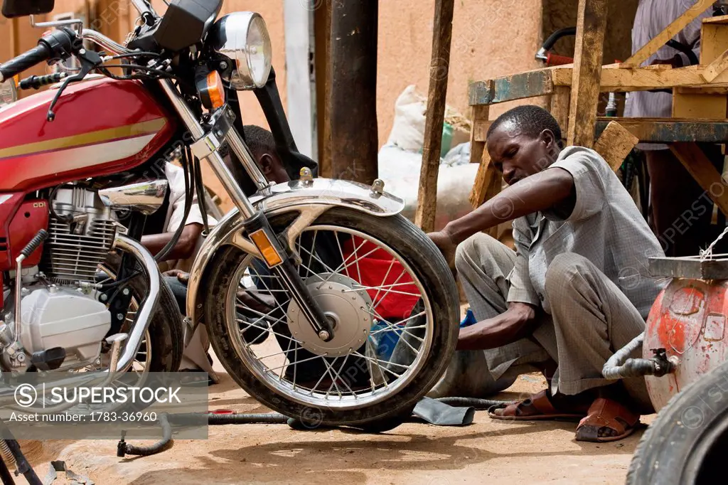 Niger, Air Region, Hausa Mechanic Fixing Motorbike In Back Street; Agadez