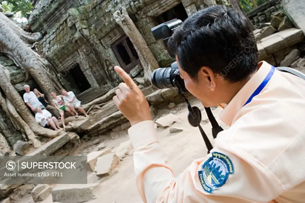Man taking photo group of people at temple of Ta Prohm,, Siem Reap, Cambodia