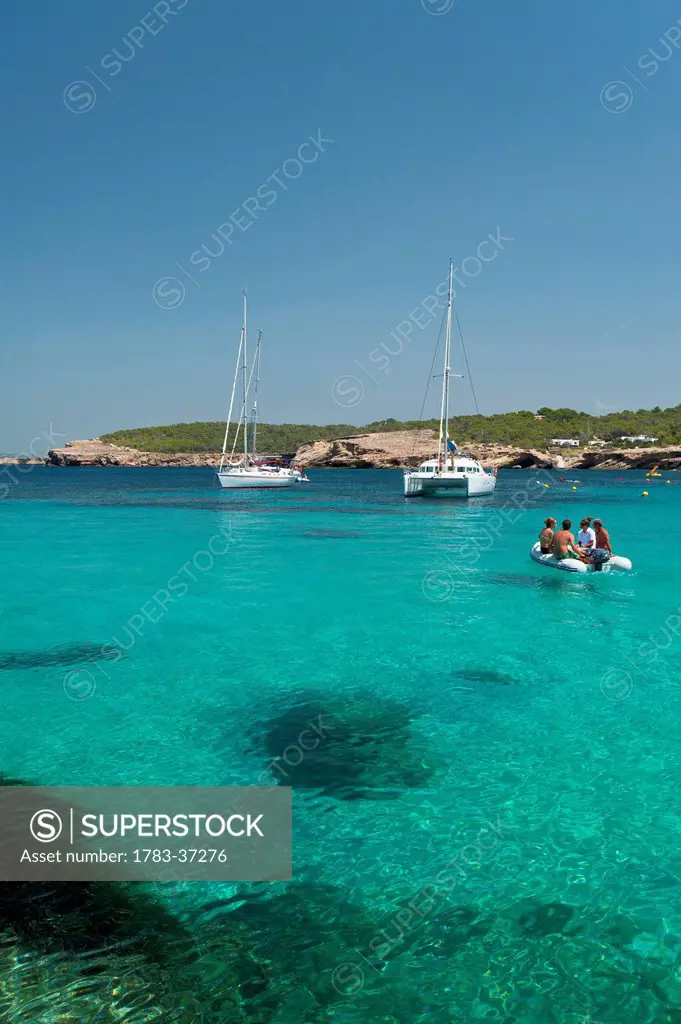 People in small boat going out to their yacht off Cala Bassa Beach; Ibiza, Spain