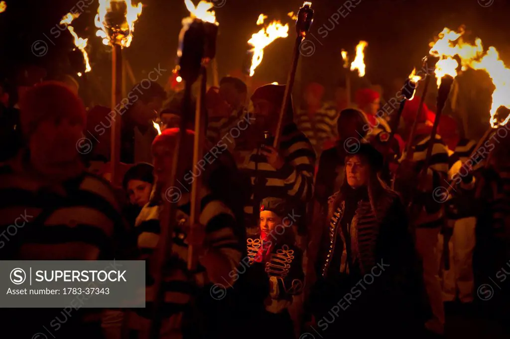 People marching along street with burning torches at Nevill Junior Bonfire Night; Lewes, East Sussex, England, UK
