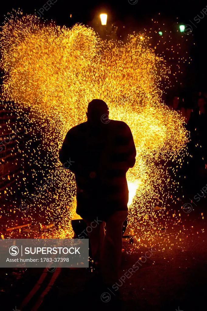 Man dragging barrel with shower of embers on Bonfire Night; Lewes, East Sussex, England