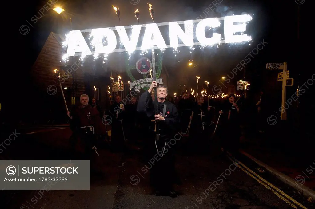 Man dressed as monk carrying 'Advance' banner on Bonfire Night; Lewes, East Sussex, England