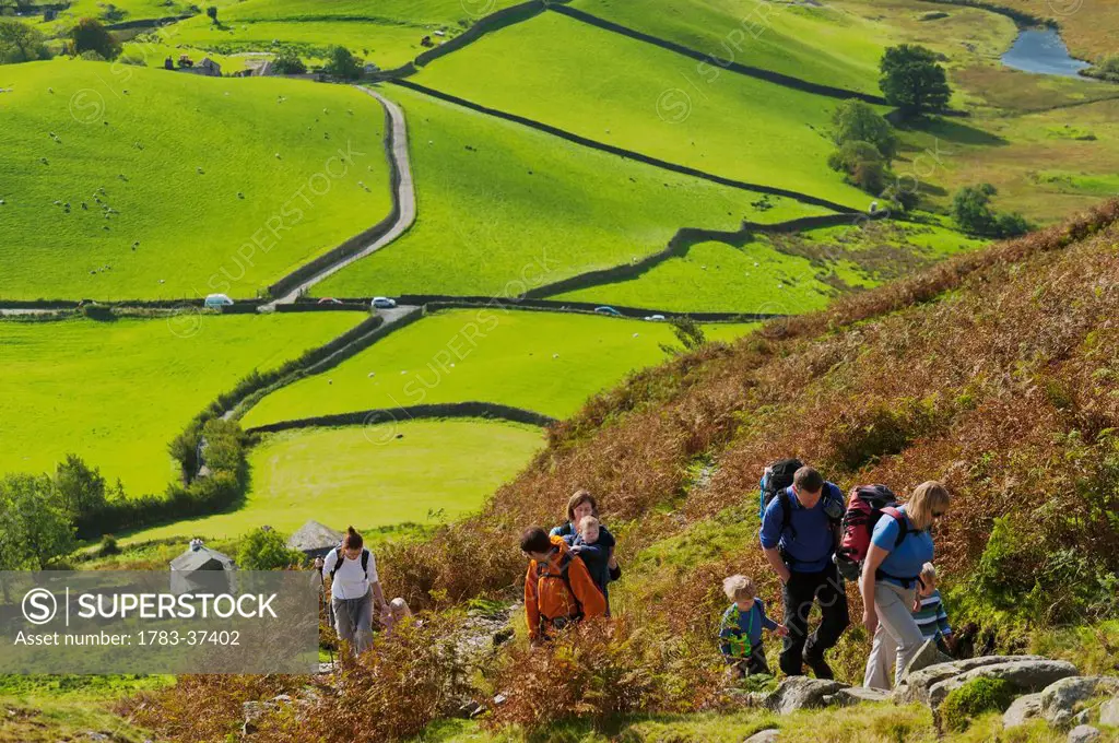 Parents leading children up path; Little Langdale, Lake District National Park, Cumbria, England