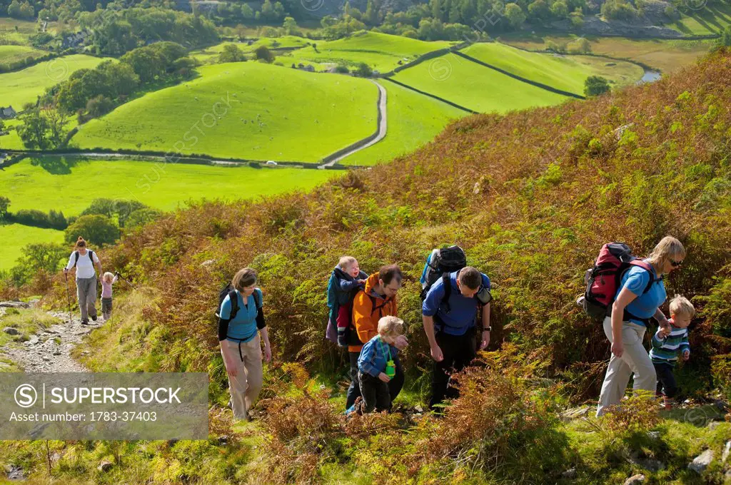 Parents leading children up path near Little Langdale; Lake District National Park, Cumbria, England