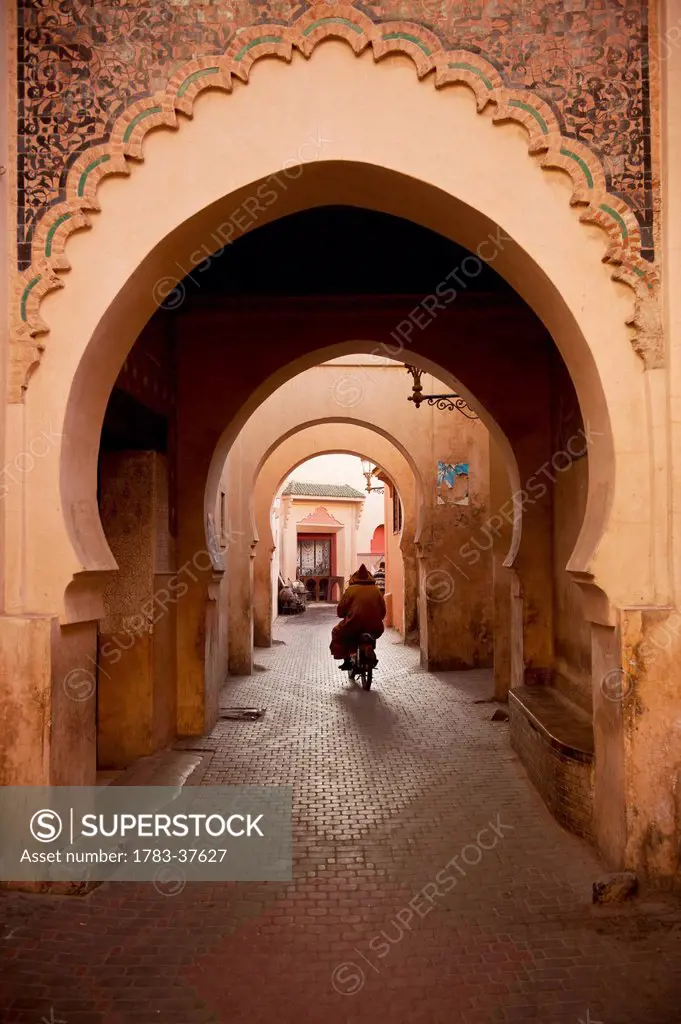 Man on moped going through arches in alleyway in Medina of Marrakesh; Marrakesh, Morocco