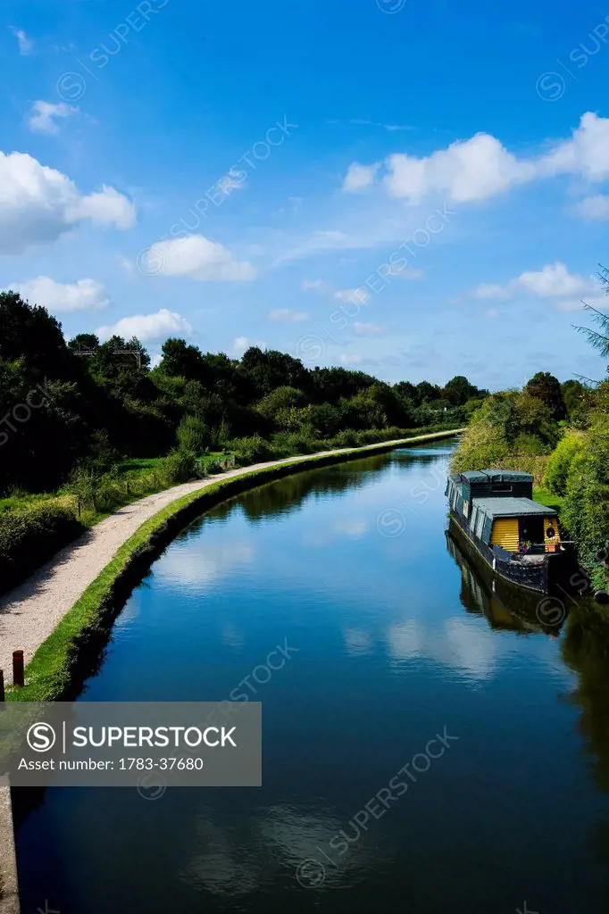 The Grand Union Canal, towpath, barge, and lush green surrounding countryside; Hemel Hempstead, Hertfordshire, UK