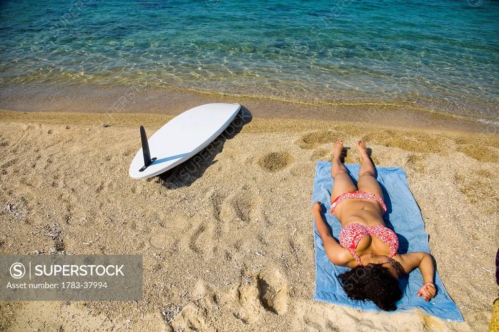 Young woman sunbathing on beach; Ierissos, Halkidiki, Greece