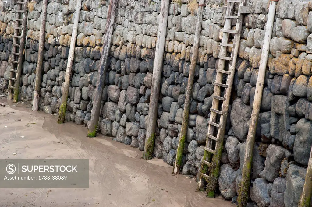 Wooden ladders and pillars at harbor during low tide; Clovelly, North Devon, UK