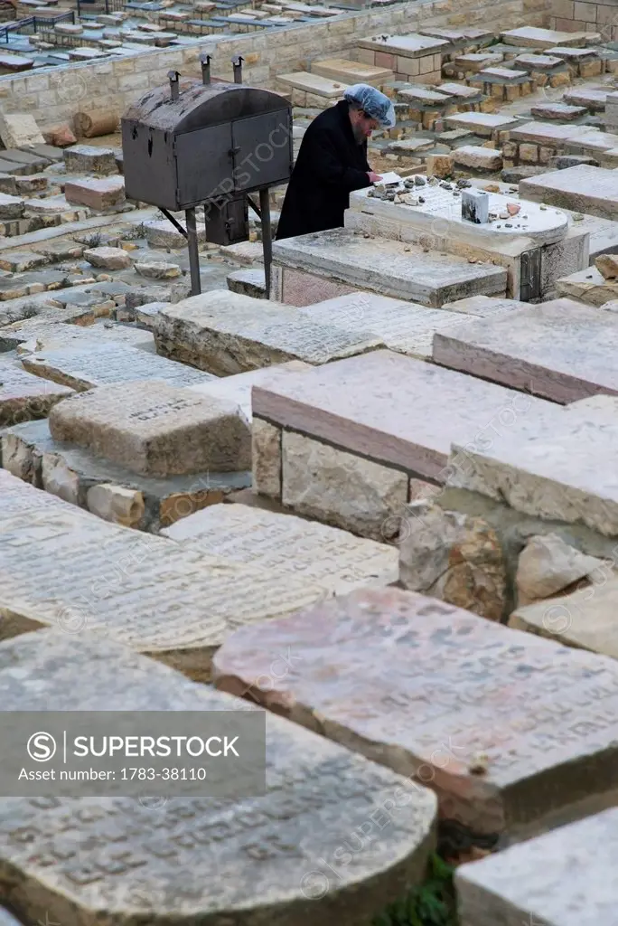 Orthodox Jew praying at tomb at Mount of Olives cemetery; Jerusalem, Israel
