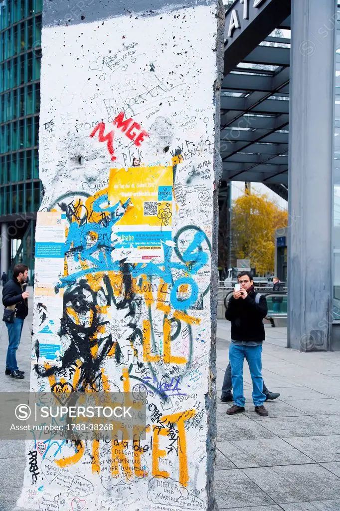 Tourists watching pieces of original Berlin Wall, Potsdamer Platz; Berlin, Germany