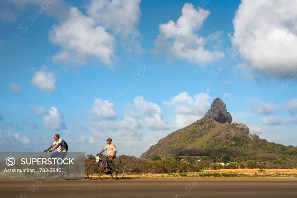 Cyclists and Morro do Pico in background; Fernando de Noronha, Pernambuco, Brazil