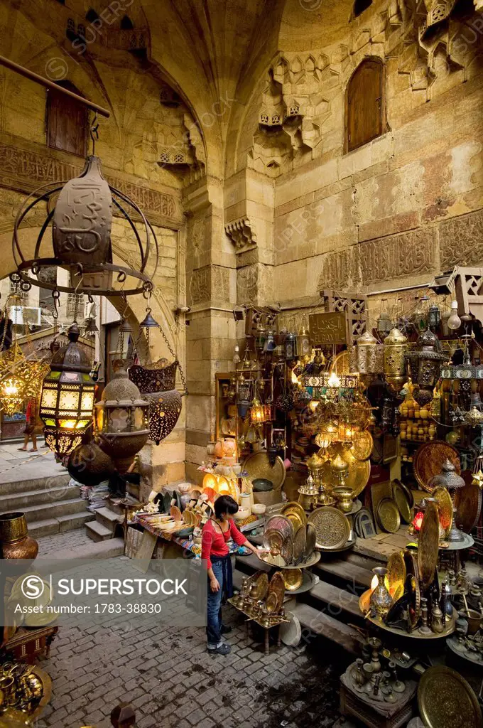 Woman shopping at stalls in covered gateway in Khan El Khalili; Cairo, Egypt