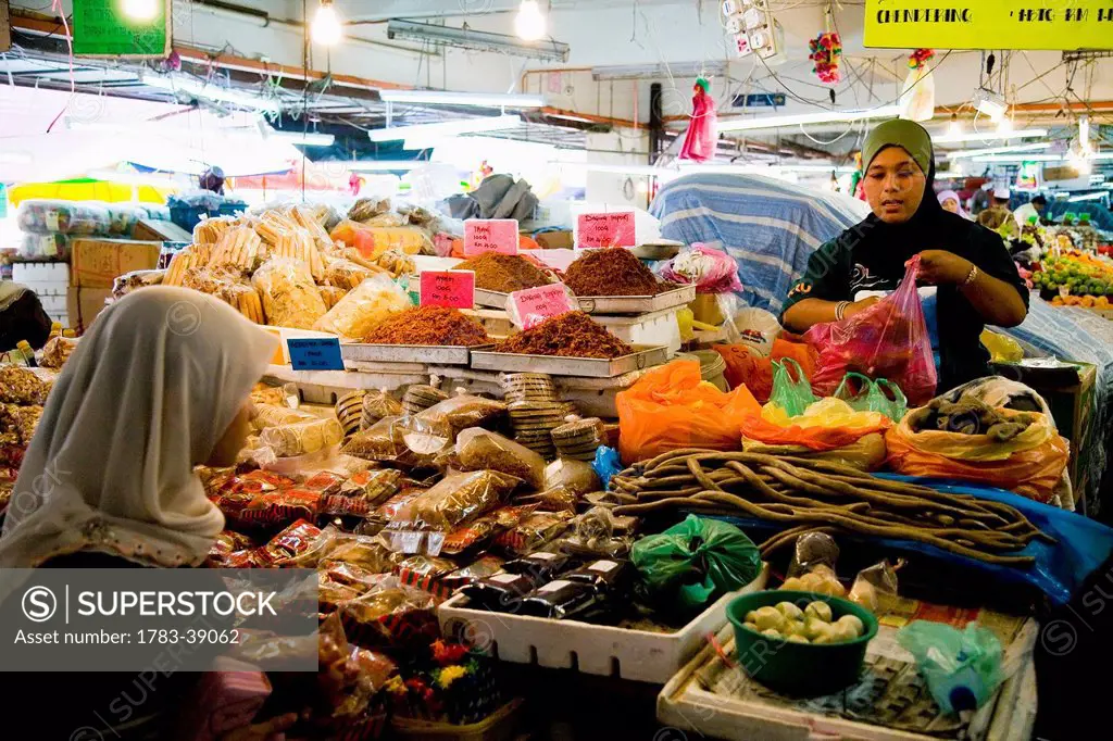 Muslim women selling fruits, vegetables and other goods at large indoor Pasar Payang central market; Kuala Terengganu, Terengganu, Malaysia