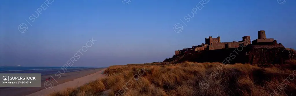UK, England, Northumberland, Northumbrian Coast, Panoramic view of sunset over Bamburgh Castle and beach; Bamburgh