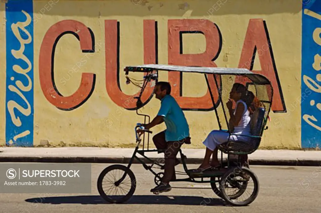 A Ricksaw passes a Viva Cuba sign, Havana, Cuba 