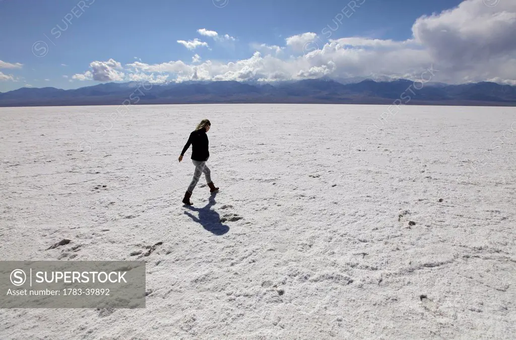 USA, California, Young woman walking across Badwater Salt flats; Death Valley National Park