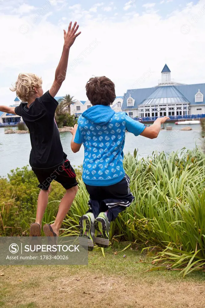 South Africa, Garden Route, Boardwalk shopping mall in background; Port Elizabeth, Boys jumping in air